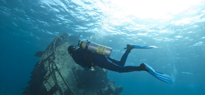 Diver exploring underwater shipwreck.