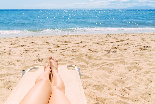 Woman sunbathing her legs on the beach